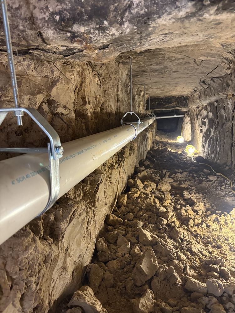 Under-slab sewer tunnel with new 4 inch PVC on hangers in Houston